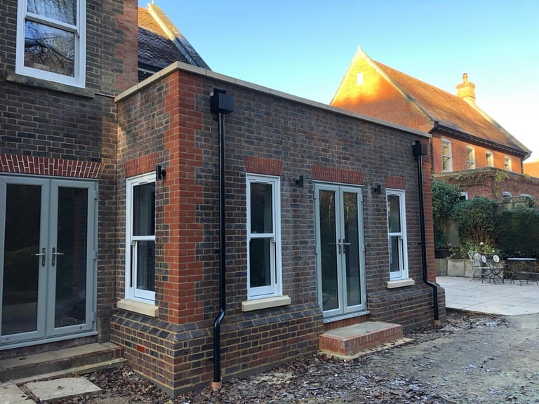 Modern brick extension on traditional brick house with large windows and patio area