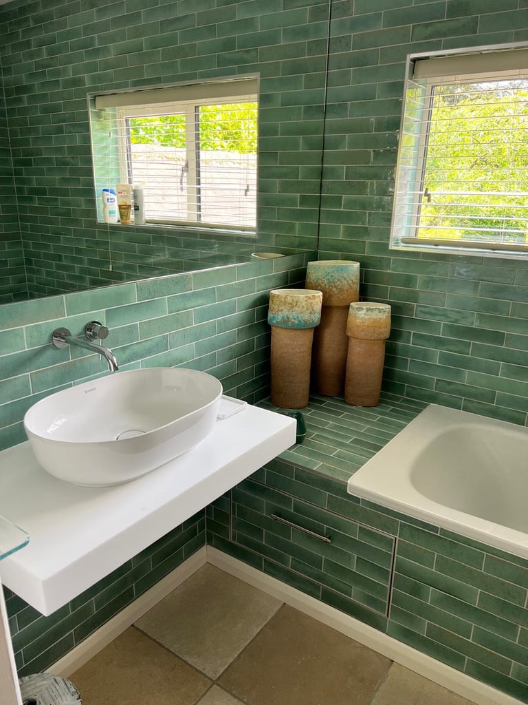 Modern green tile bathroom with white vessel sink, soaking tub, and decorative baskets